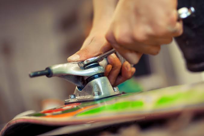 Hands fitting trucks to a skateboard deck in the Soul workshop